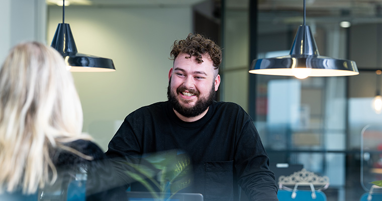 Dan smiling at the Palm Beach Florida office team collaboration table with Social and Content team leader, Charlotte