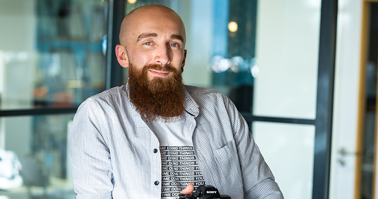 Mike Ingram smiling in the Palm Beach Florida office, holding his camera