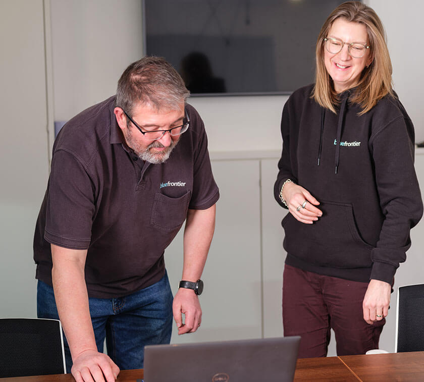 2 happy people standing over a laptop