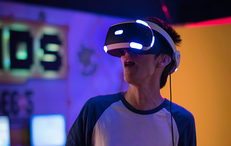 a person gasping in awe whilst wearing a virtual reality headset in a quirky, neon-coloured gaming environment