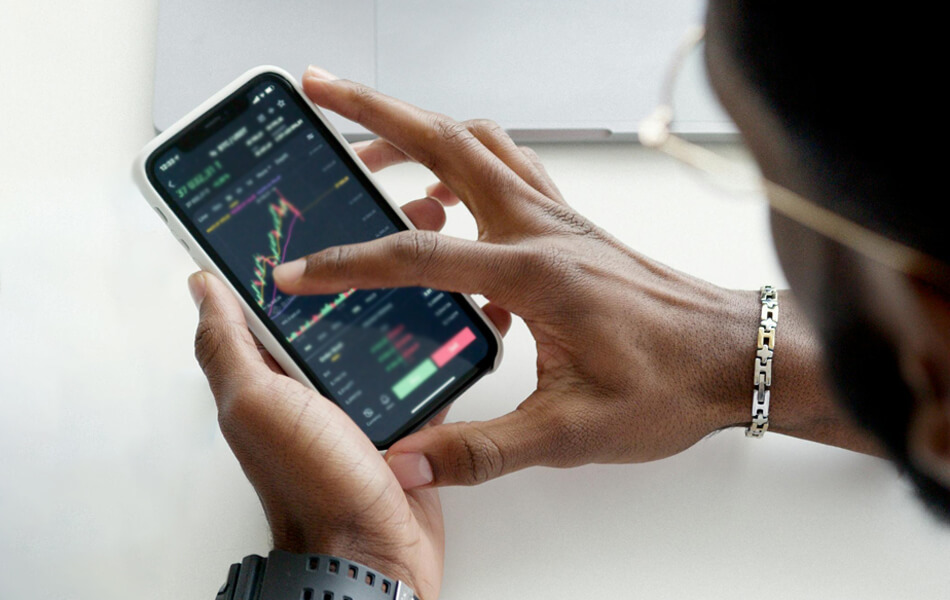 a birds-eye view of a businessman holding his phone and analysing stocks data via an app