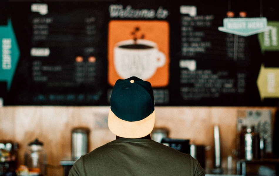 a confused customer stands in front of a large cafe menu