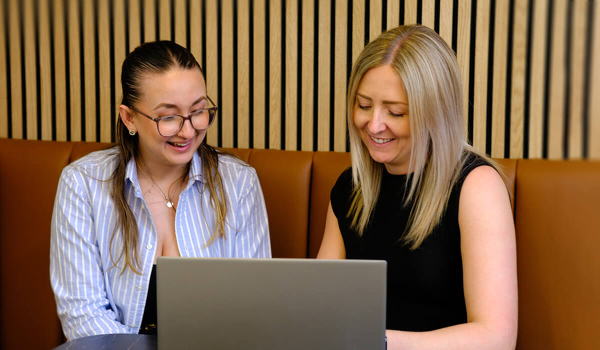 two digital marketers looking at a laptop together in a contemporary office space