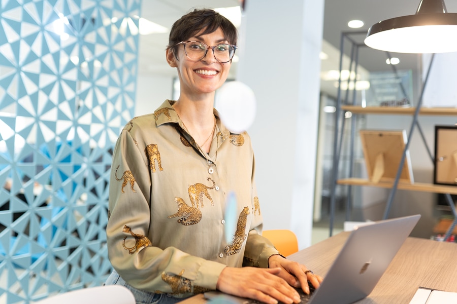 A friendly colleague smiling and working on their laptop