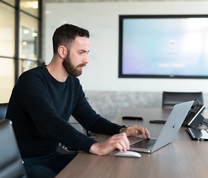 A web designer concentrates on their laptop inside a large meeting room