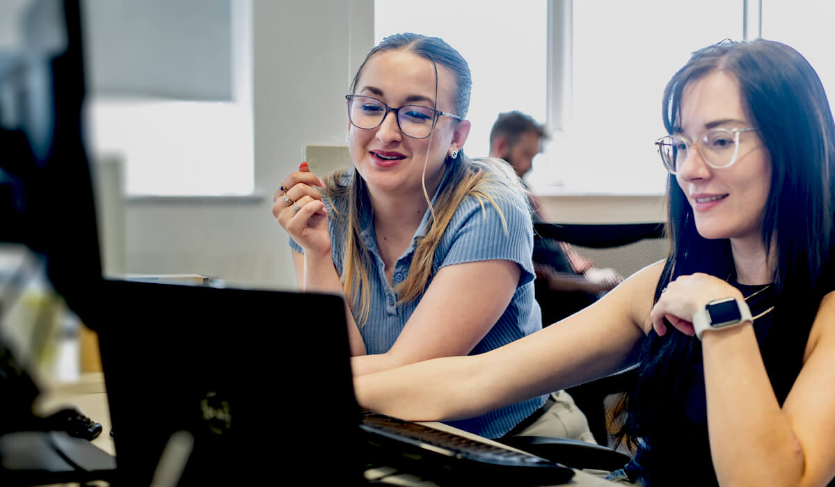 two colleagues sitting together discussing campaign results at a computer desk