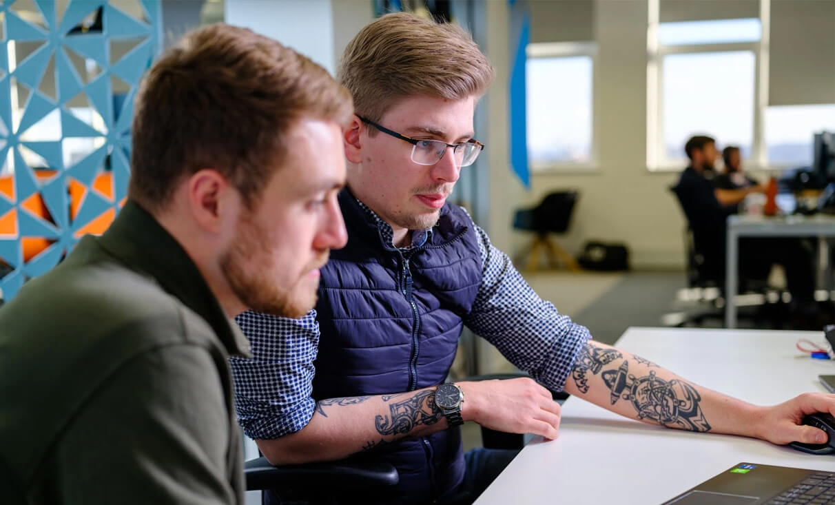 two web developers troubleshooting an issue with a website in a bright office space